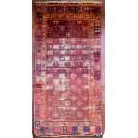 An antique Tabat carpet with repeating gul motifs across the deep red field contained within a
