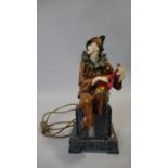 An Art Deco style resin court jester playing the mandolin light, he is sitting on a stepped marble