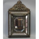 A 19th century Dutch brass framed repousse cushion mirror with scrolling arched cresting and