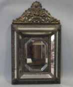 A 19th century Dutch brass framed repousse cushion mirror with scrolling arched cresting and