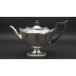 A Victorian silver tea pot with ebony handle and finial with scalloped design. Hallmarked: TB for