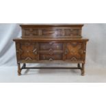 A mid century oak Jacobean style sideboard with raised panelled superstructure above doors and