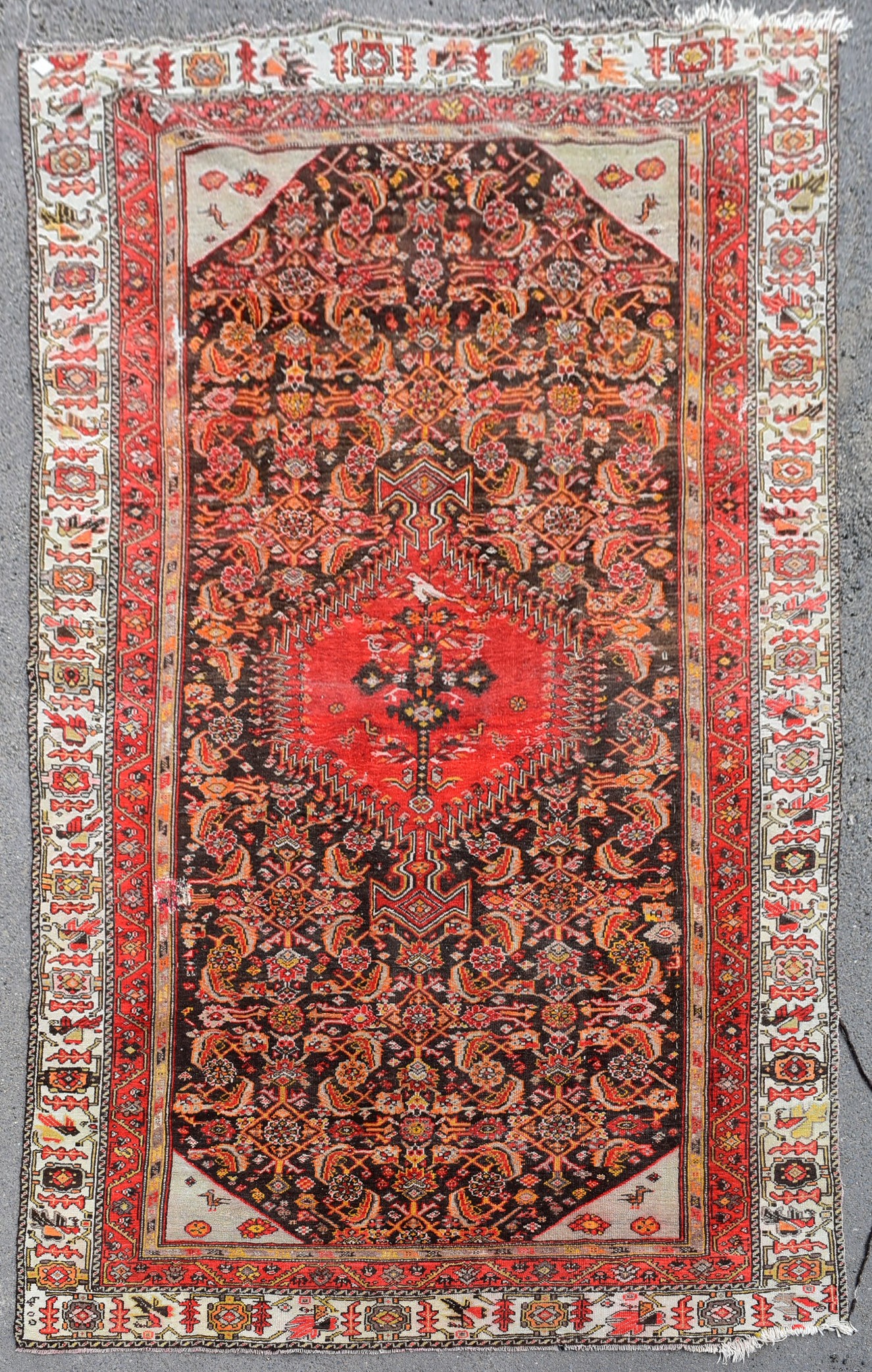 An antique Persian Malayer carpet with central hooked pole medallion on a stylised floral field