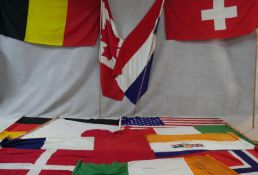 A miscellaneous collection of thirteen various vintage national flags along with three flag poles.