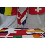 A miscellaneous collection of thirteen various vintage national flags along with three flag poles.