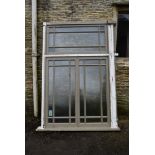 A large painted hardwood window frame of twenty seven double glazed panels with stained glass corner