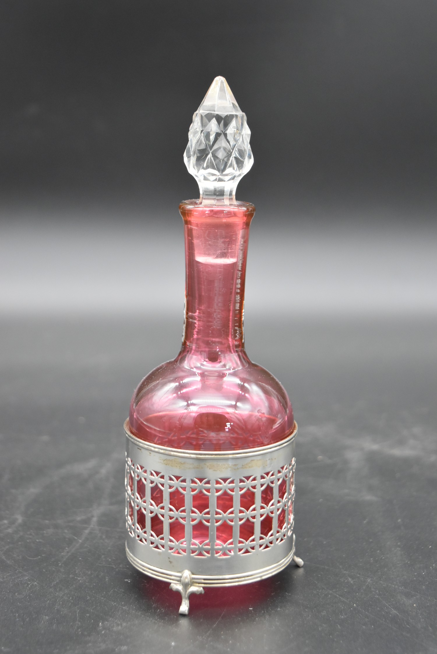 A cut cranberry glass bottle and stopper in a silver pierced stand hallmarked Birmingham 1923 - Image 4 of 6