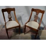 A pair of early 19th century walnut dining chairs with satinwood scroll inlay to the back rail and