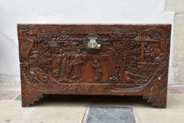 A Chinese camphor coffer with all over relief carved decoration of figures, birds and foliage in