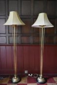 A pair of heavy brass standard lamps with floral decoration and matching shades standing on ebonised