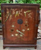 A lacquered Japanese cabinet with bi-fold doors and all over painted exotic bird and blossom