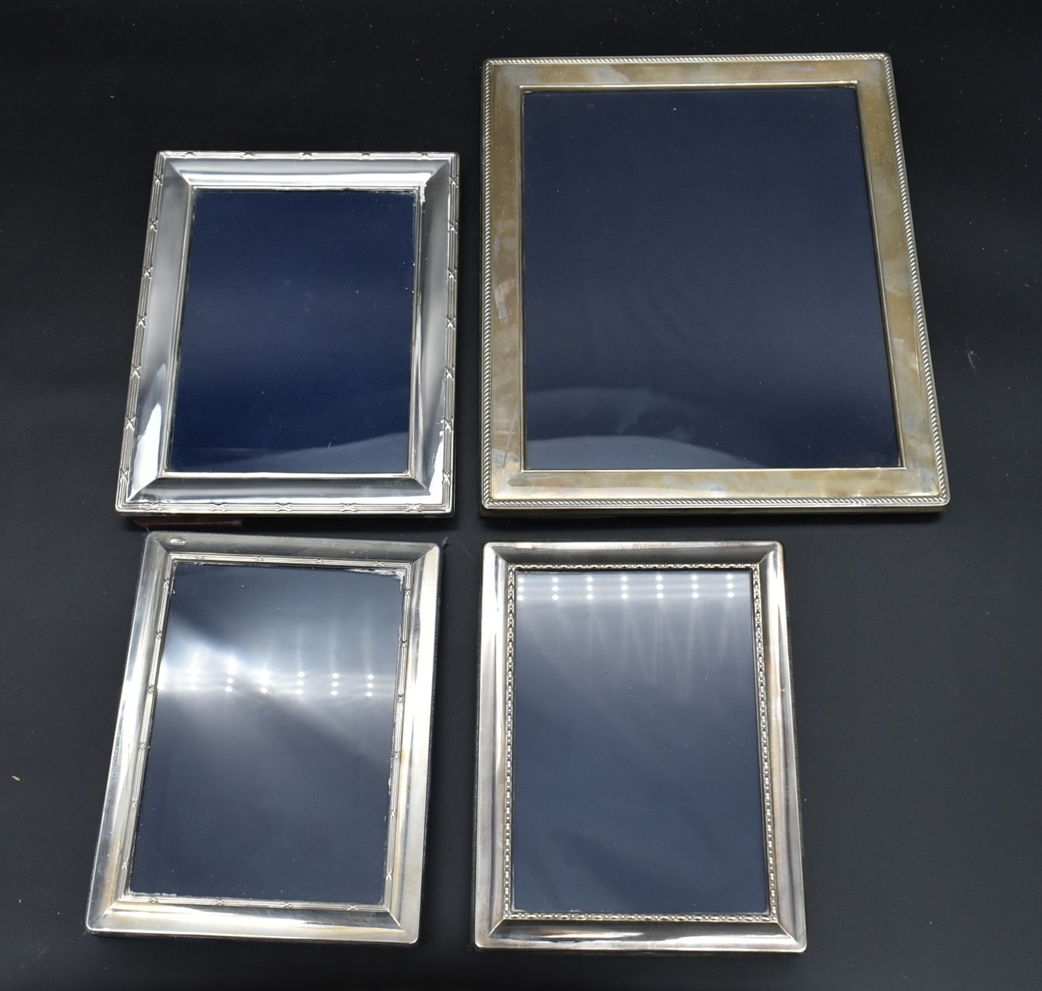 A collection of four silver easel picture frames each bearing an English hallmark. H.30cm W.25cm (