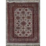 A Eastern carpet with repeating floral motifs across the fawn field within stylised geometric