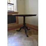 A Georgian mahogany tilt top table with central turned pedestal on tripod cabriole pad foot