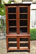 A late 19th century twin section walnut bookcase with glazed panel doors enclosing bookshelves to