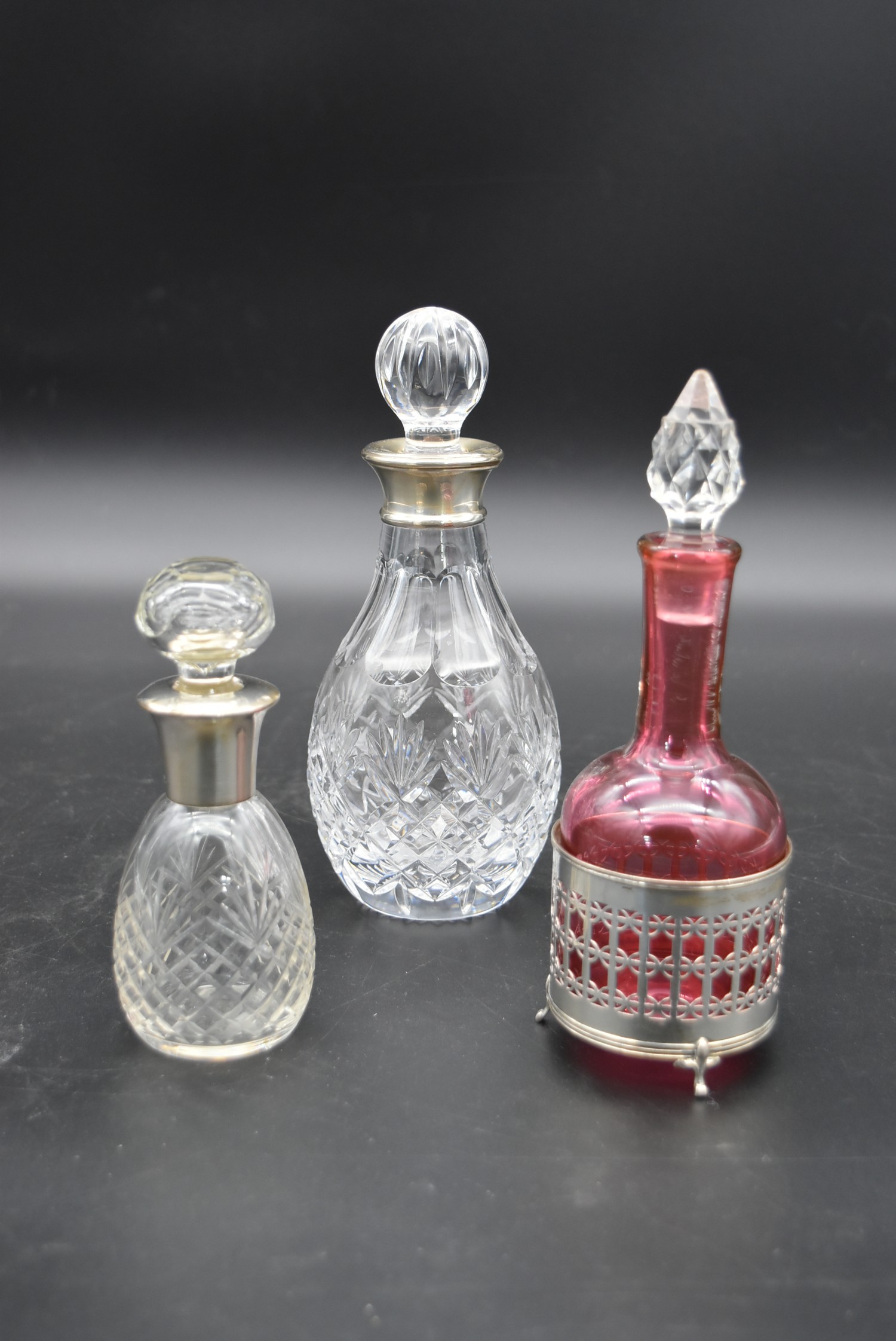 A cut cranberry glass bottle and stopper in a silver pierced stand hallmarked Birmingham 1923