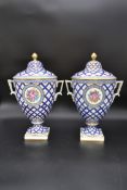 A pair of lidded Dresden urns with gilt finials and blue and gold lattice work glaze with painted