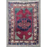 A Kazak rug with central midnight medallion on madder ground contained by stylised spandrels