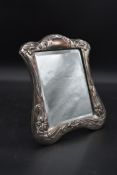 An Art Nouveau silver embossed dressing table mirror with bevelled plate and scrolling floral