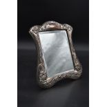 An Art Nouveau silver embossed dressing table mirror with bevelled plate and scrolling floral