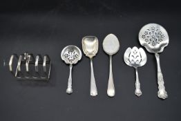 A collection of five 19th century and later English silver spoons along with a silver toast rack,