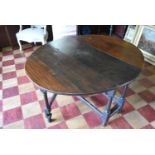 An antique oak drop flap dining table fitted with end drawer on turned and stretchered gateleg