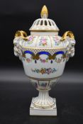 A Dresden neo classical style hand gilded and decorated lidded urn with twin ram's head handles