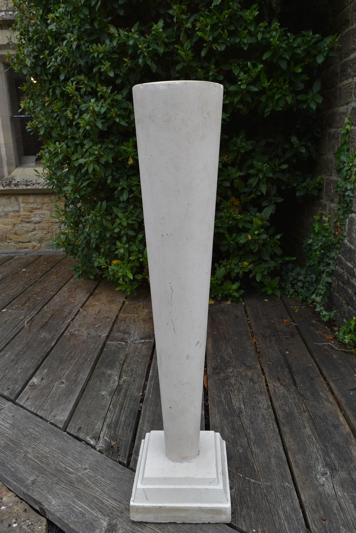 A tall stone tapering plinth on stepped base. H.105cm