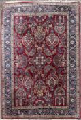 An Eastern carpet with repeating floral sprays and palmettes across the madder ground contained