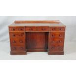 A 19th century mahogany pedestal desk with an arrangement of drawers and kneehole cupboard on plinth
