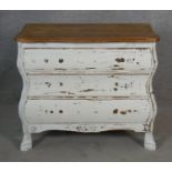 A small distressed painted French bombe style chest with shaped oak top above three long drawers
