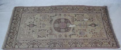 An Eastern carpet with central floral medallion and stylised flowerhead decoration on a fawn