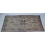 An Eastern carpet with central floral medallion and stylised flowerhead decoration on a fawn