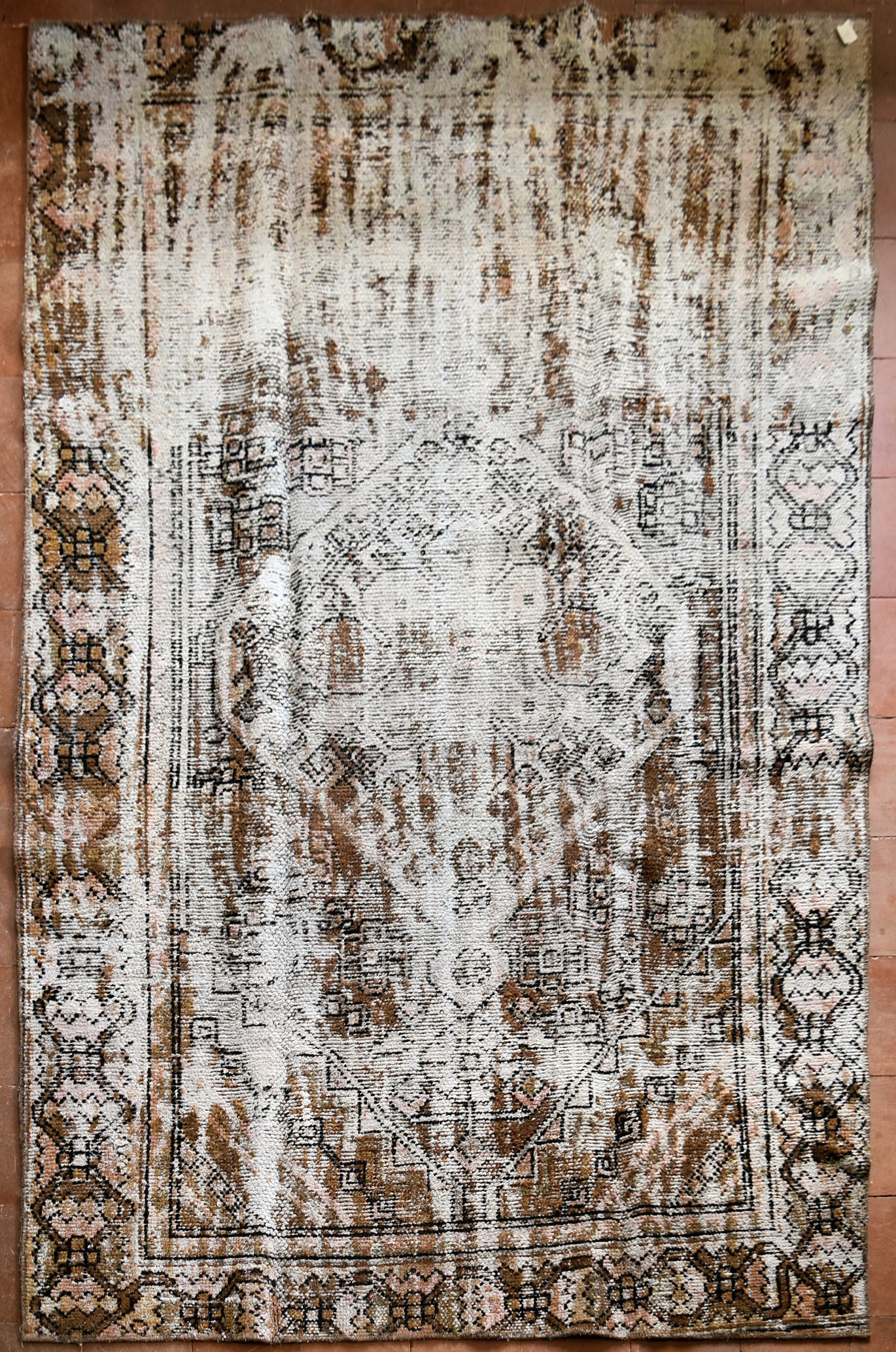 A re-dyed distressed effect Persian carpet with central diamond medallion within stylised borders.