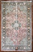 A Kashmir silk rug with floral medallion and spandrels on a salmon ground depicting animals in a