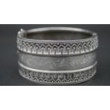 A Victorian engraved white metal cuff bangle with wirework detailing and foliate garland design.