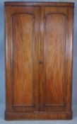 A 19th century mahogany wardrobe with arched panel doors enclosing hanging space (one side