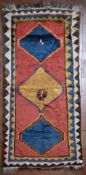 An old Persian Gabbeh rug with repeating diamond medallion on a blush ground within serrated