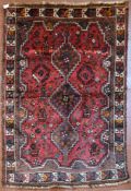 A Persian Shiraz rug with triple stepped pole medallion on burgundy field with stylised animal and