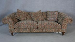 A Victorian style buttoned back Chesterfield sofa in tapestry style upholstery on turned tapering