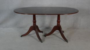 A Georgian style mahogany dining table with extra leaf on twin tripod pedestal bases. H.76 L.217 W.
