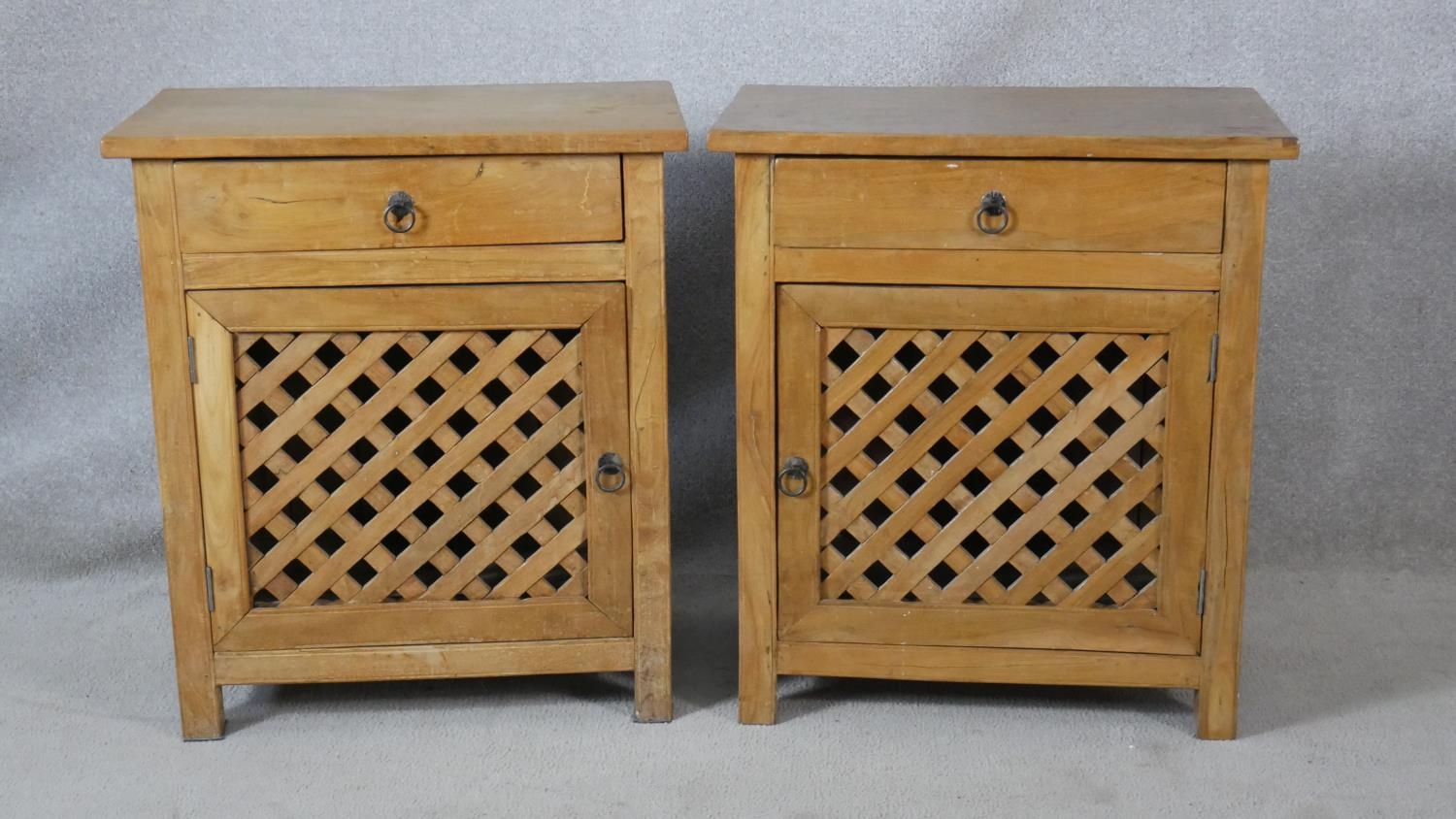 A pair of Eastern hardwood bedside cabinets with frieze drawers above lattice panelled cupboard