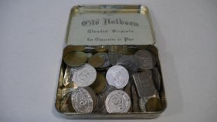 A vintage tin filled with a large collection of antique and vintage shop, gaming and other tokens.