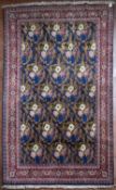 A silk and wool Persian Kashan rug with repeating floral motifs within gilt scrolling vines on an