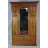 An Edwardian mahogany and satinwood strung wardrobe with bevelled mirror door enclosing hanging