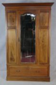 An Edwardian mahogany and satinwood strung wardrobe with bevelled mirror door enclosing hanging