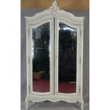 A French carved and painted armoire with Rococo cresting above a pair of bevelled plate glass