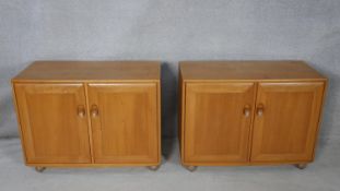 A pair of mid century vintage blonde elm Ercol Windsor cabinets, each with fitted interior on