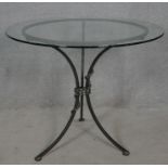 A plate glass topped conservatory table on wrought metal tripod base. H.78 D.91.5cm