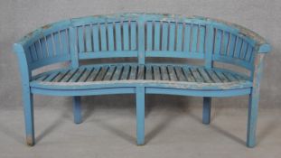 A vintage distressed painted teak garden bench of curved outline. H.83 W.158 D.60cm
